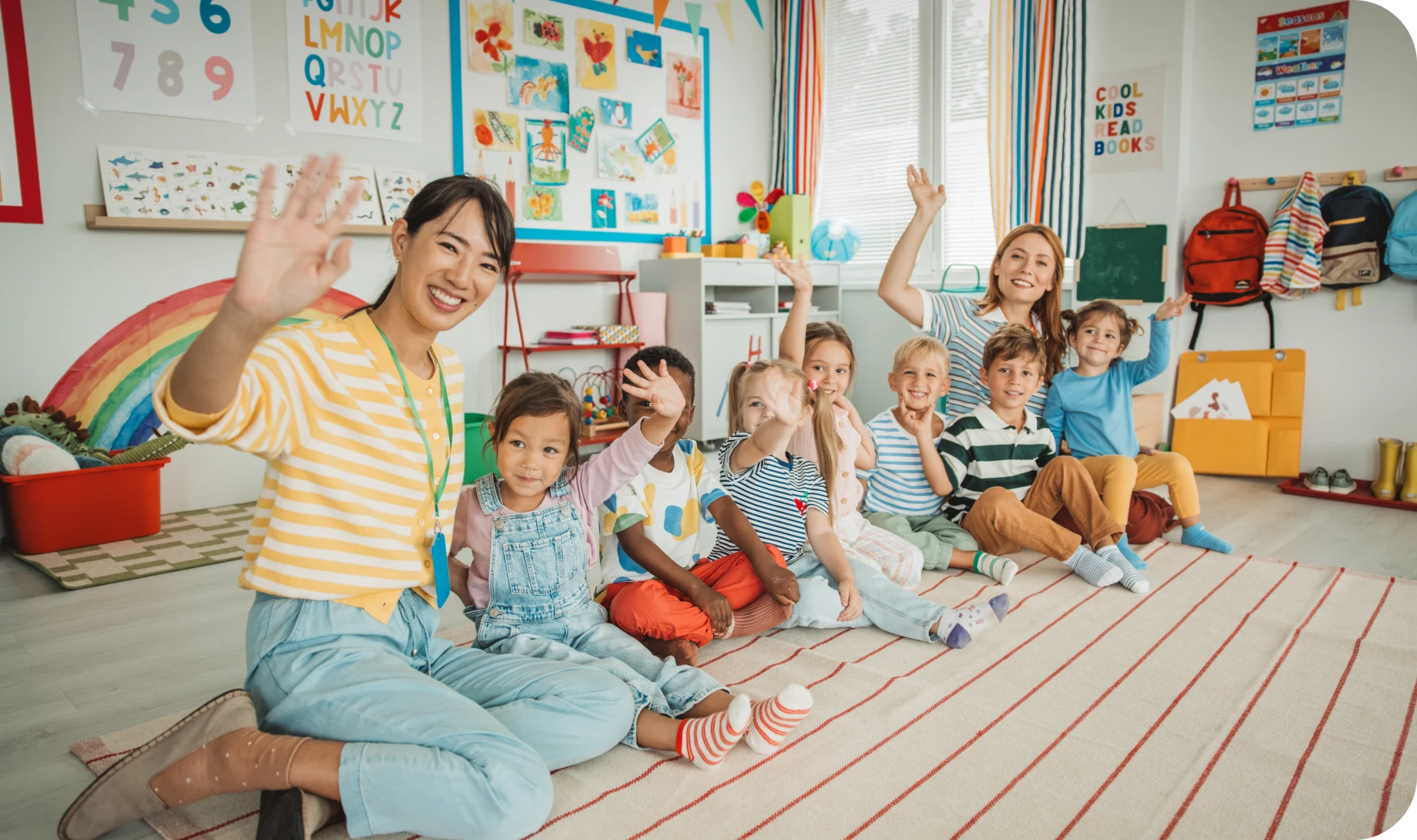 Children and teachers waving in classroom